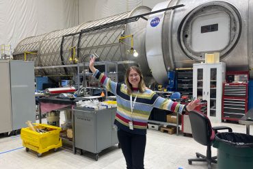 Katie Davis standing in front of Microfluidic Electrochemical Reactor