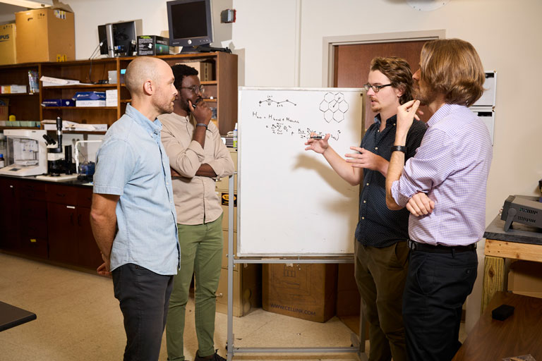 Grad students work with professors on white board