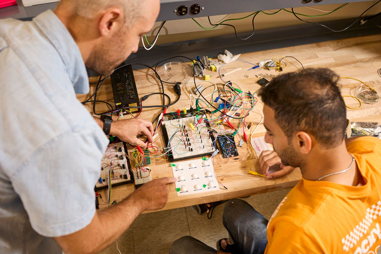 Professor works with student on mother boards 