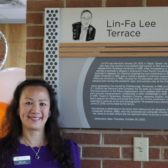 May Lee standing in front of a dedication plaque for Lin-Fa Lee Terrace.