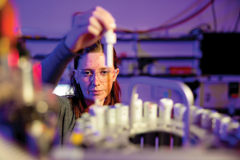 A graduate student places samples in a nuclear magnetic resonance spectroscopy