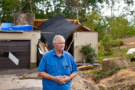 Terry Hazen standing outside his house with his damaged home behind him.