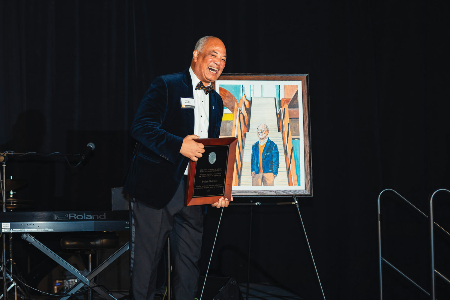 Dwight Hutchins posing for a photo with his award on stage