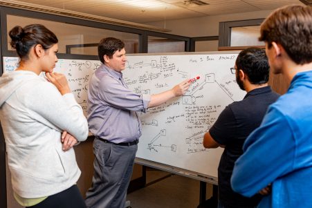 Ruoti working with college students to solve problem on white board