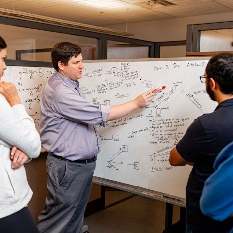 Ruoti working with college students to solve problem on white board