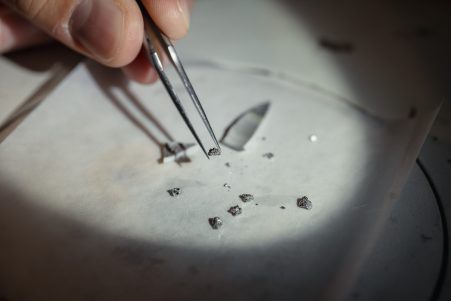 crystals being held by a pair of tweezers with a light shining on them