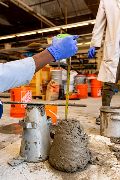 Sazzadul Saykat measures the concrete mold with a ruler and measuring tape.