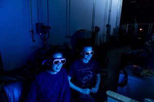 Haochen Li and a student working in the lab with a blue light illuminating them