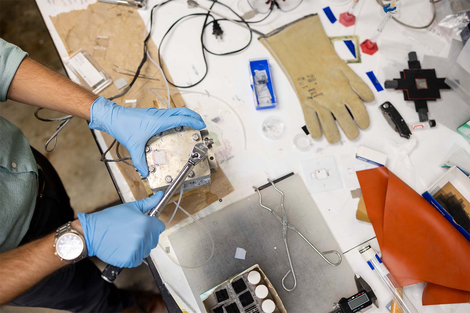 person tightening bolts on a battery in a lab