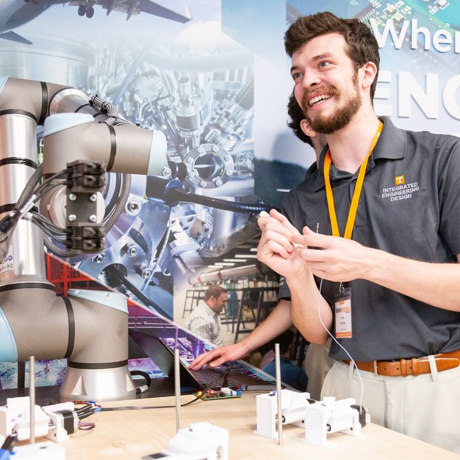 Male student smiling and holding component of interdisciplinary student design project