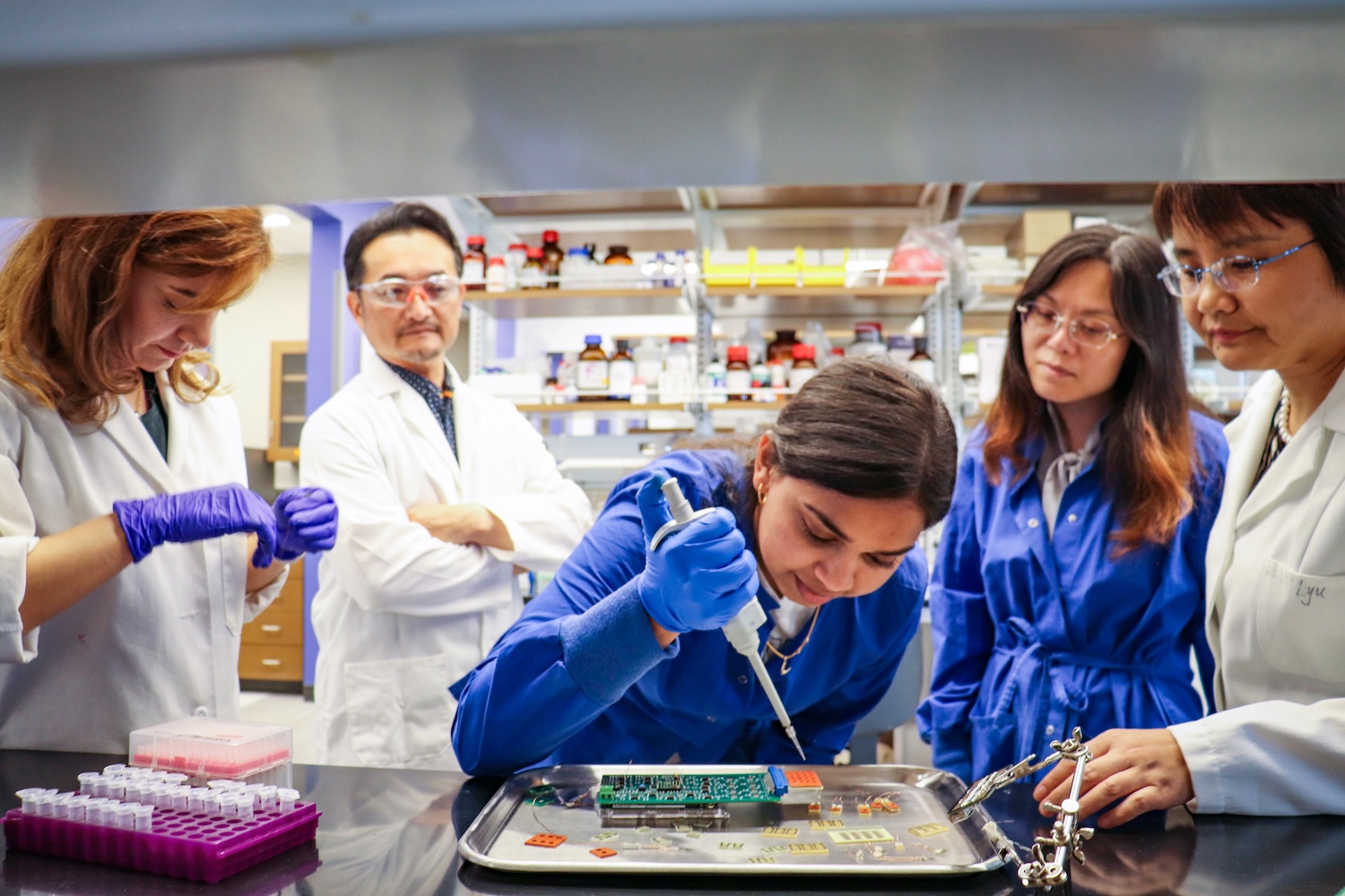 graduate student and professors in a lab