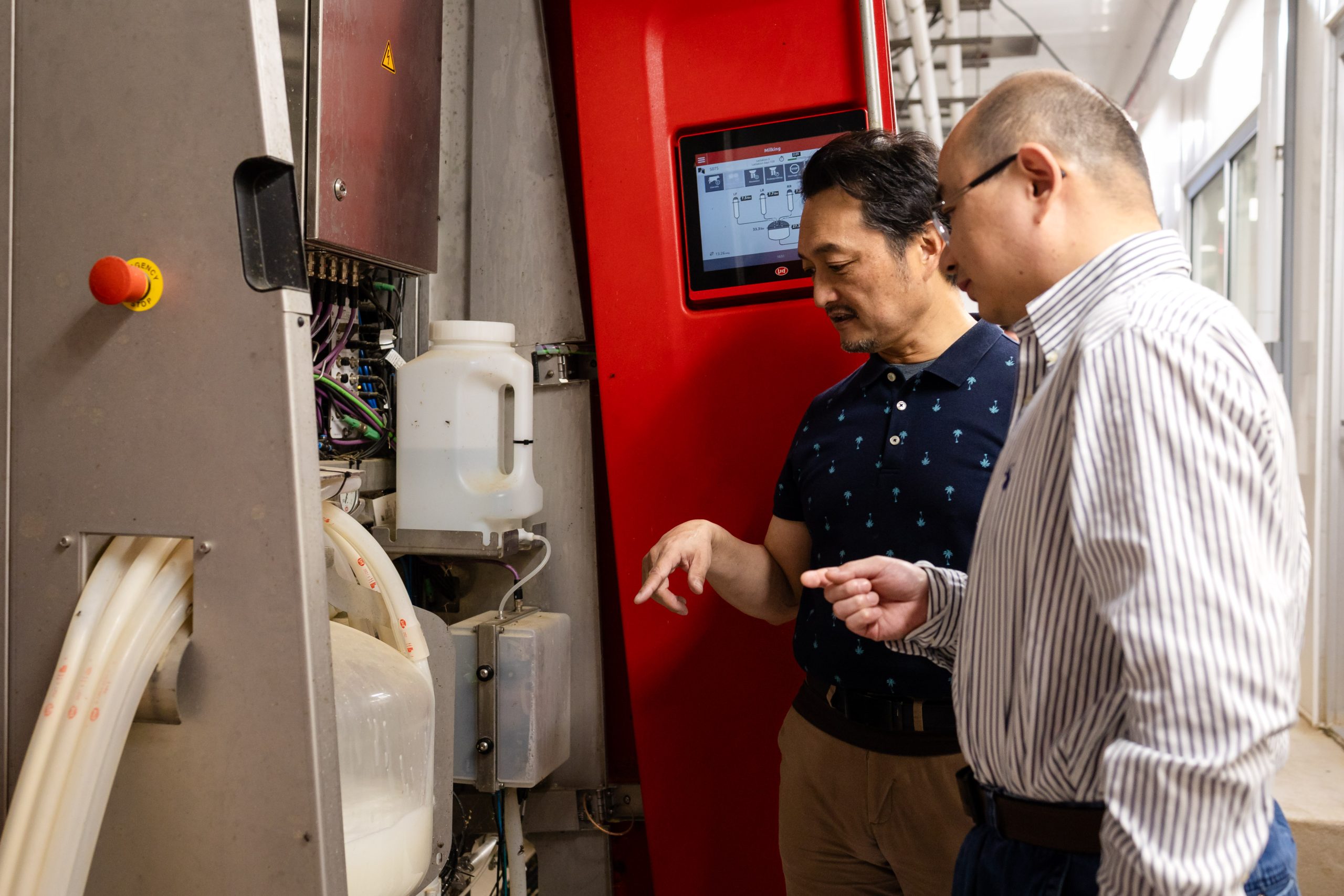 Two men pointing at a machine with liquid inside