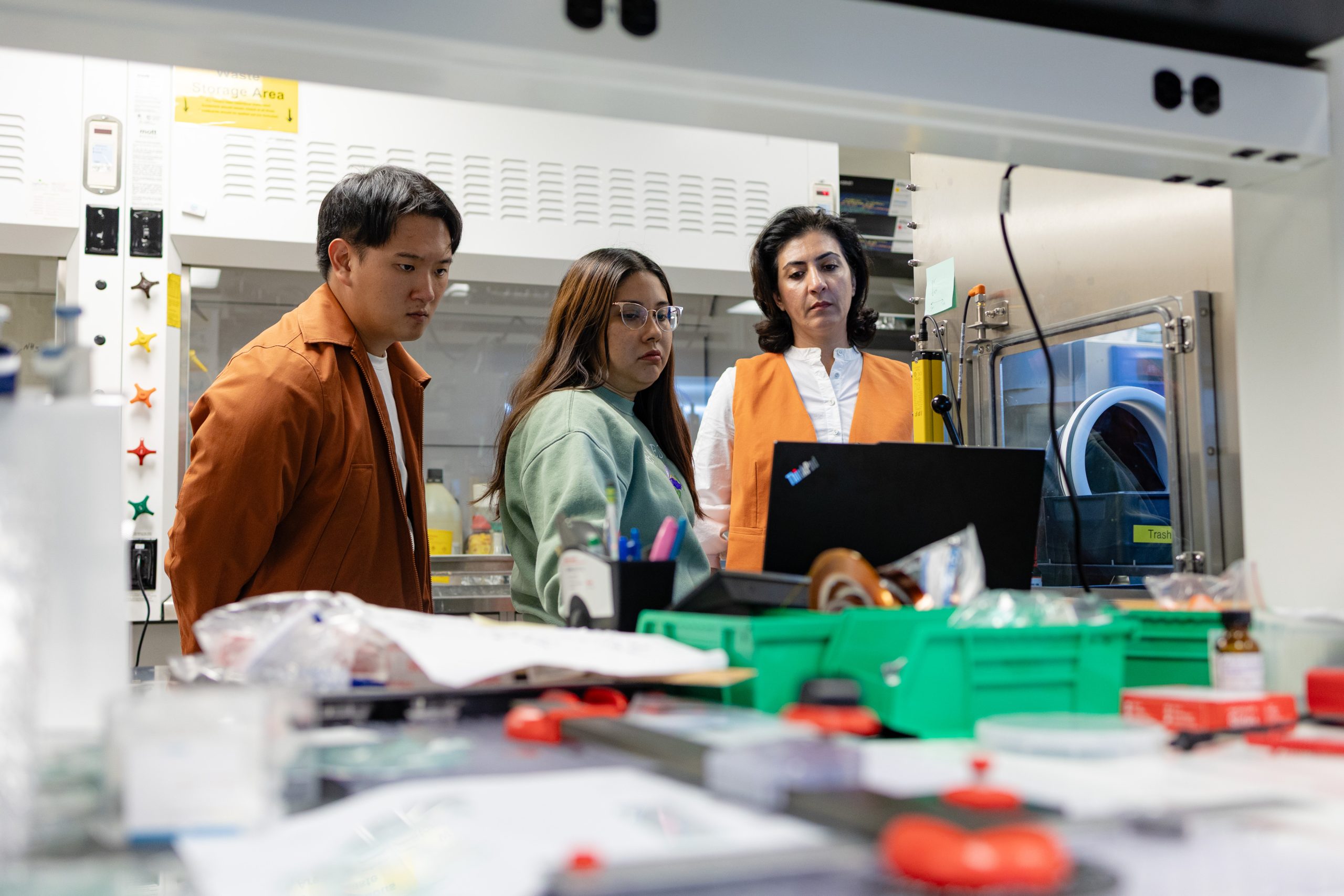 Associate Professor Mahshid Ahmadi observes a screen with two students in a lab
