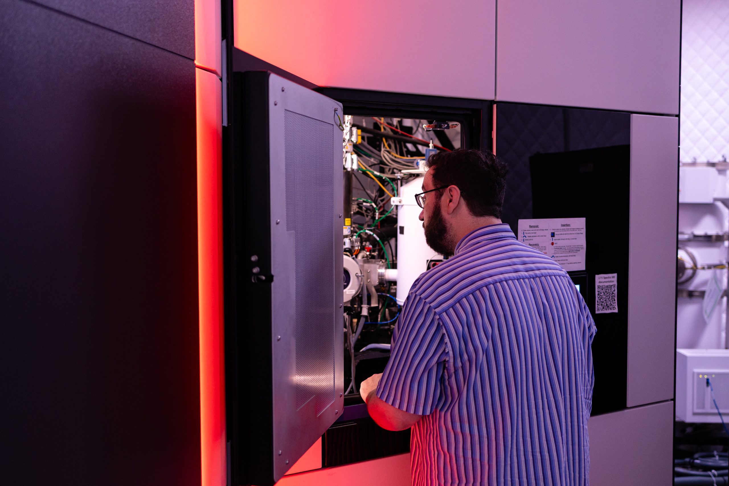 A man looks into a small room with wires and equipment