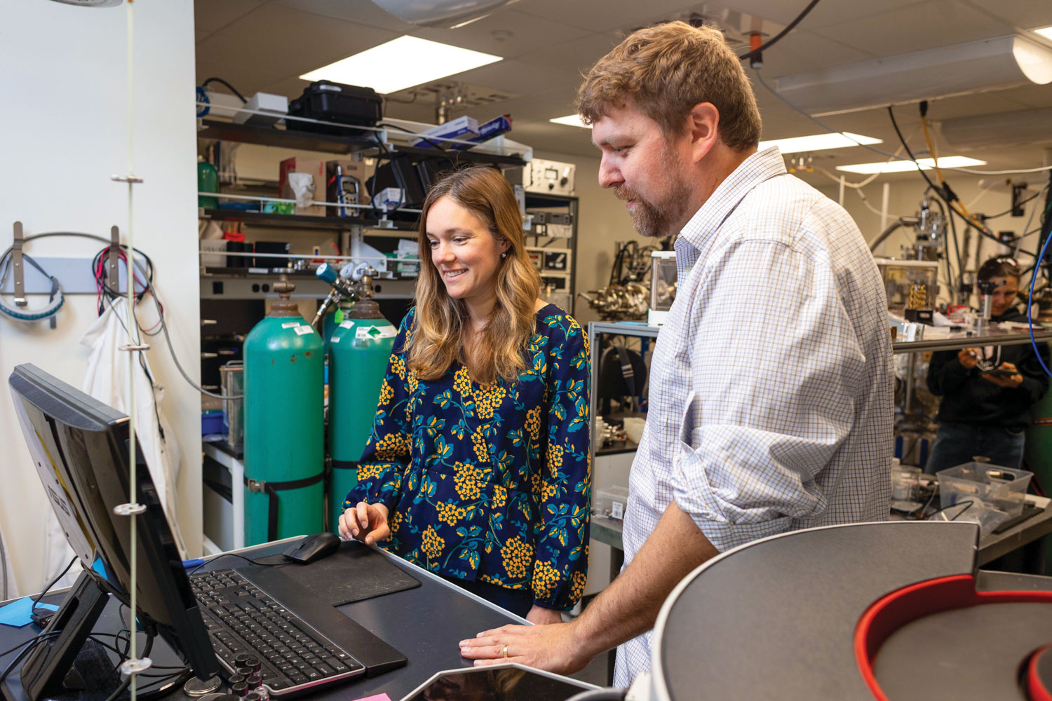 Professors Dustin Gilbert and Anne Murray look at a computer screen in a lab