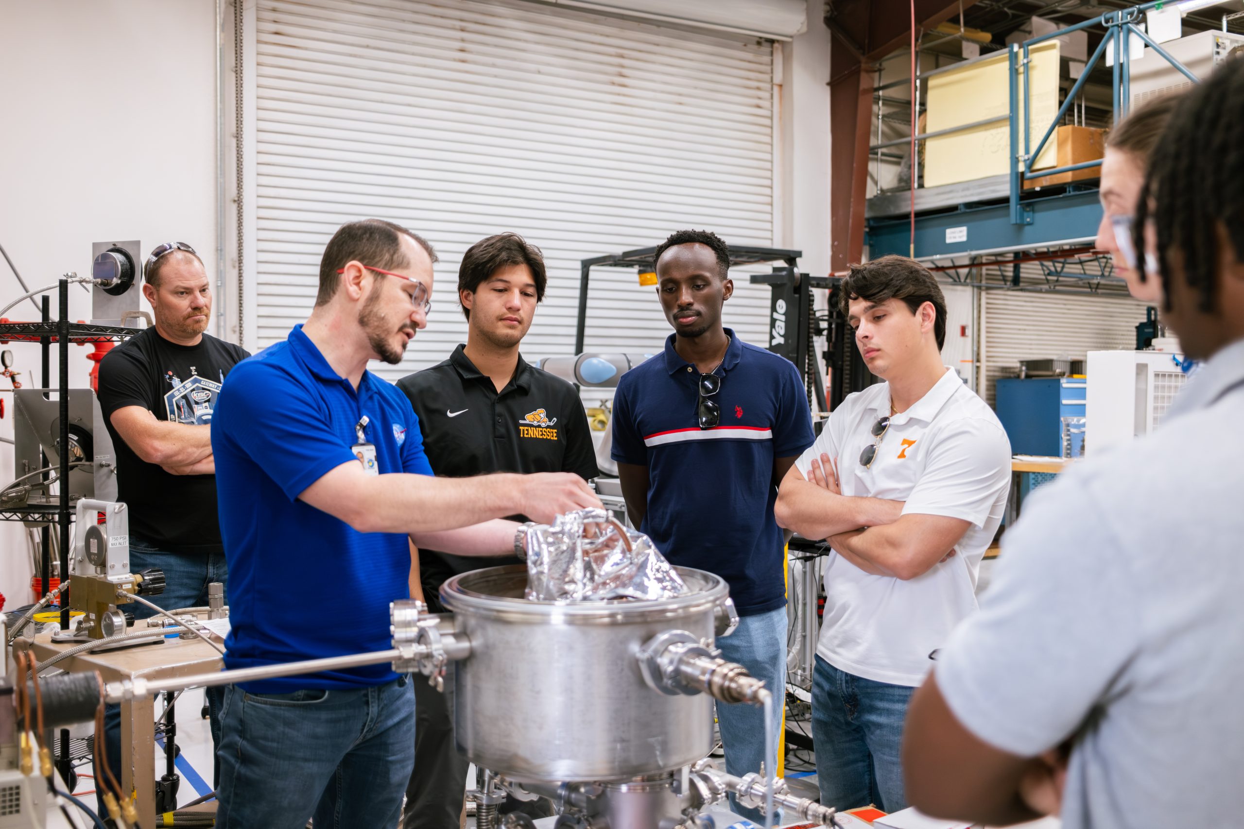 Students observe as a NASA engineer shows how a machine works