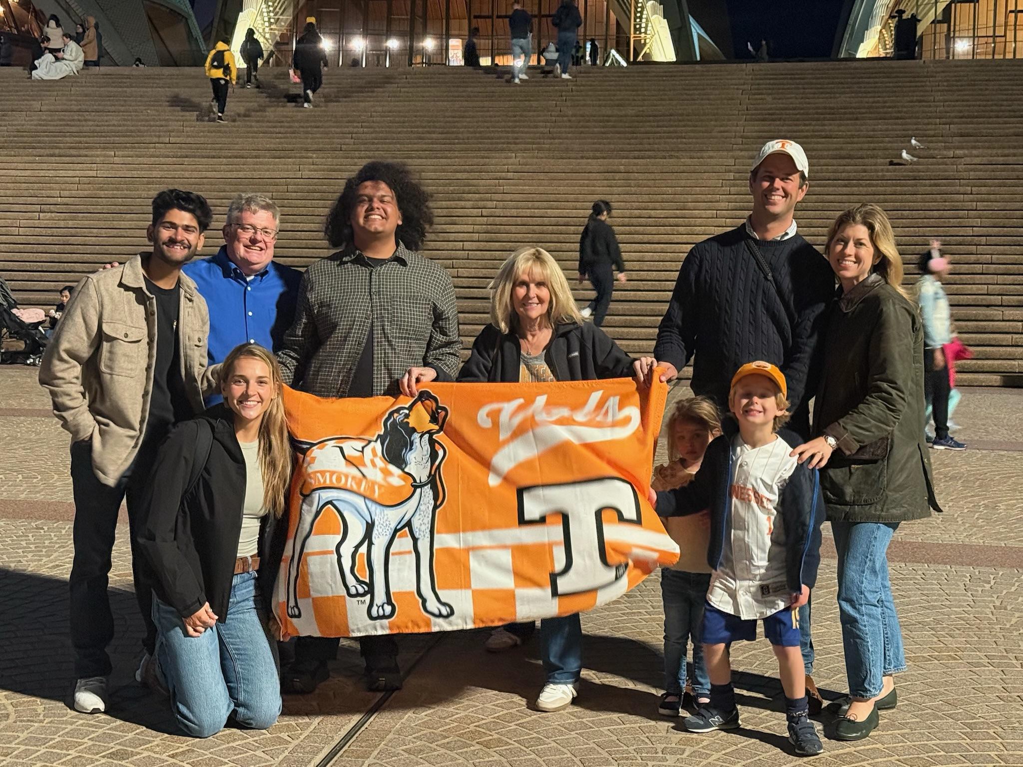 Deep Mistry, Anna Witsoe, Darrin Rhines, Connor Davis, Suzanne Sawicki, Ryan Welker, and his family holding a UT flag with Smokey on it.