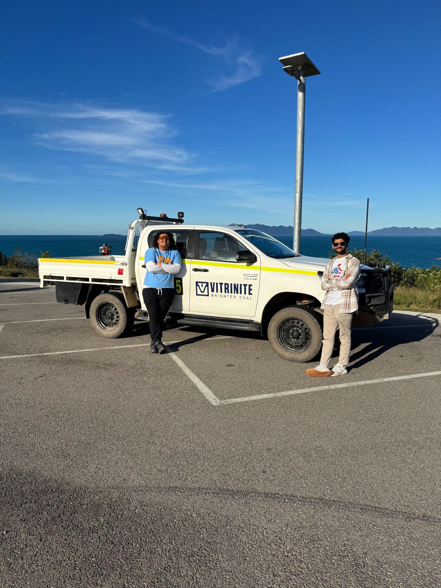 Two group members posing in front of a Vitrinite vehicle