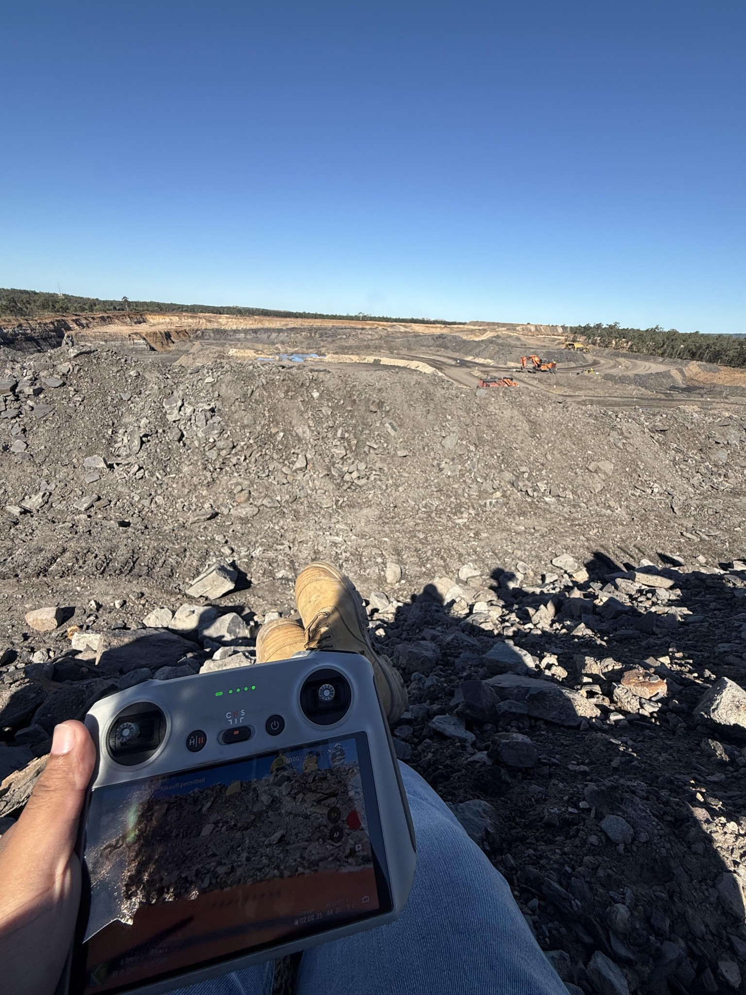 Group member sitting near a mine site while holding a radar machine