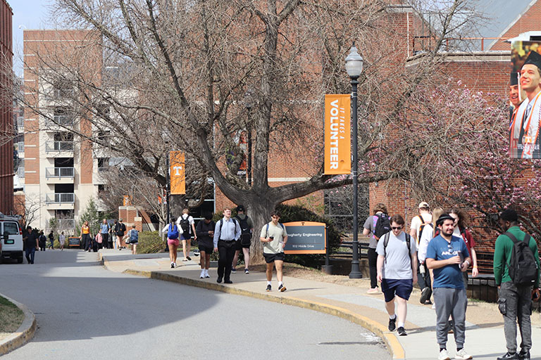 UT students walking next to the Dougherty Building on a sunny spring day