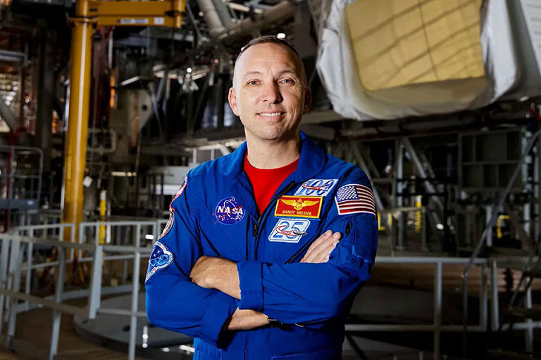 Randy Bresnik smiling with his arms crossed in a NASA uniform