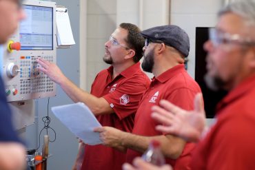 Two participants in the ACE training program work with CNC machine
