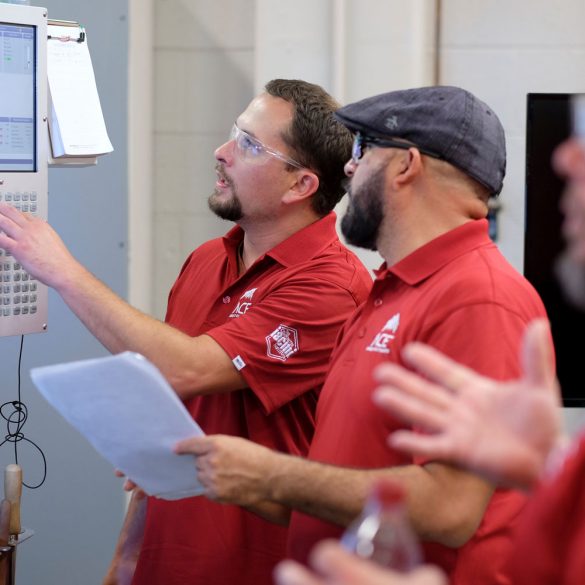 Two participants in the ACE training program work with CNC machine