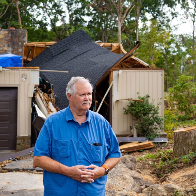 Terry Hazen standing outside his house with his damaged home behind him.