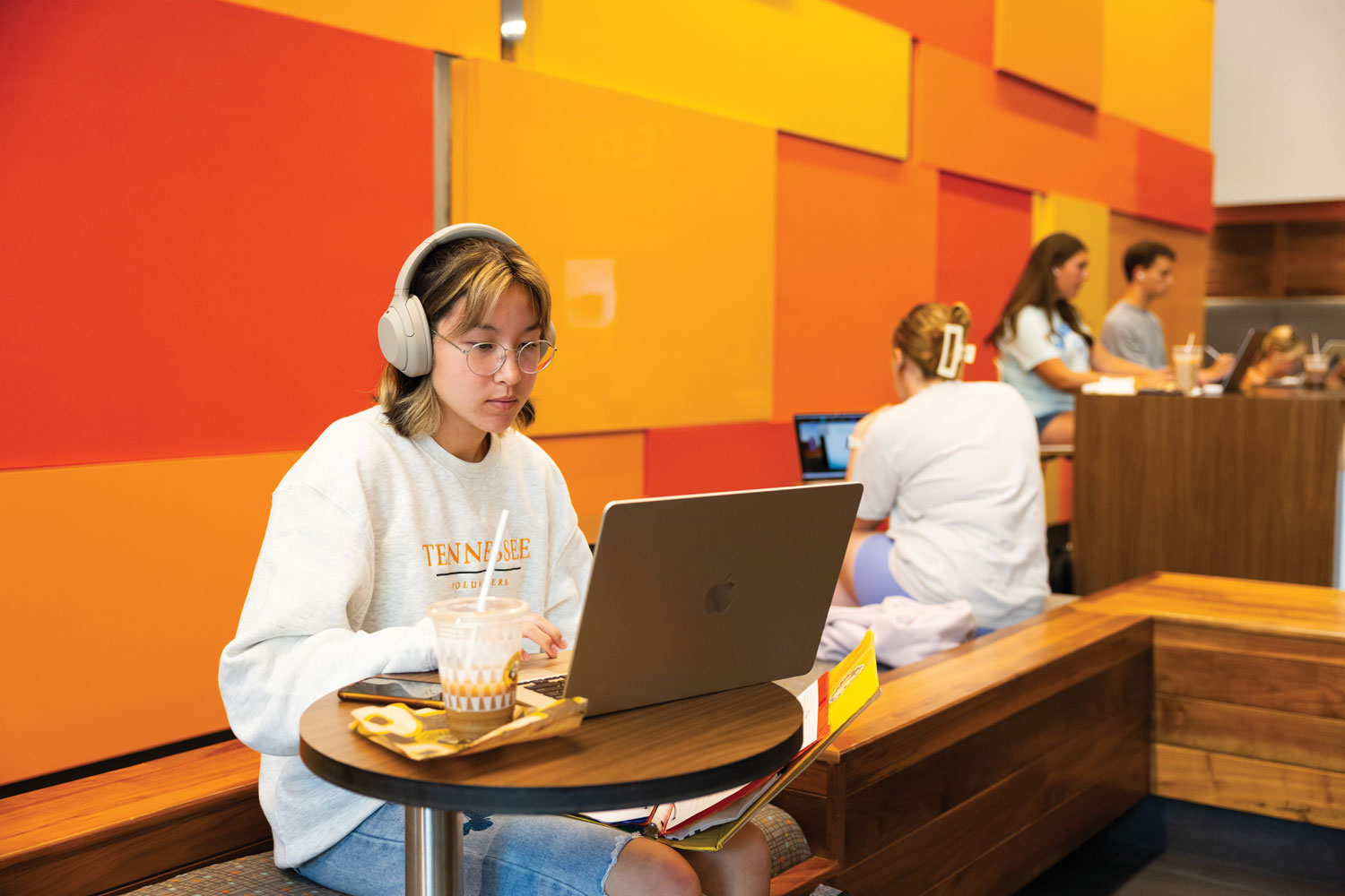 Student studying on laptop with headphones on and coffee
