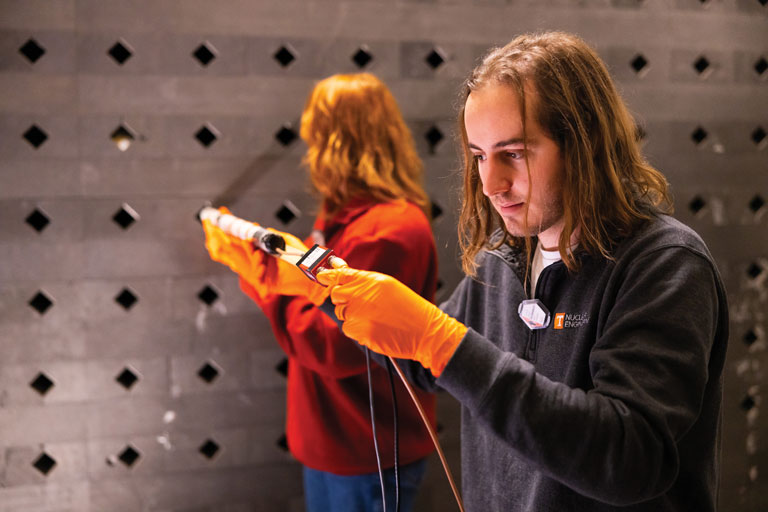 Students in Bogetic’s class take measurements with a helium-3 detector, sliding the sensor deep into the slots in the graphite pile.